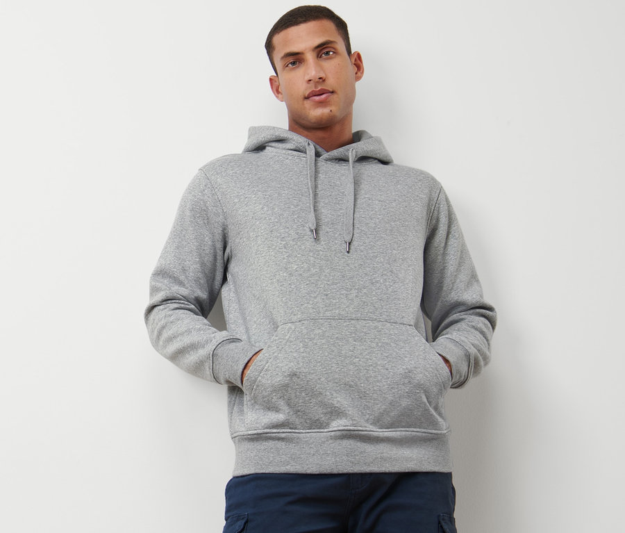 Mann posiert im Bild und trägt einen grau melierten Hoodie.