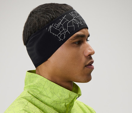 Mann mit Windprotection-Stirnband und neongrüner Jacke mit verschränkten Armen.