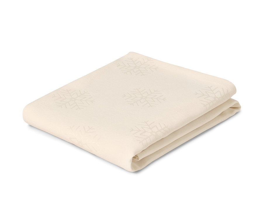 Gefaltete, cremefarbene Jacquard-Tischdecke mit Schneeflocken.