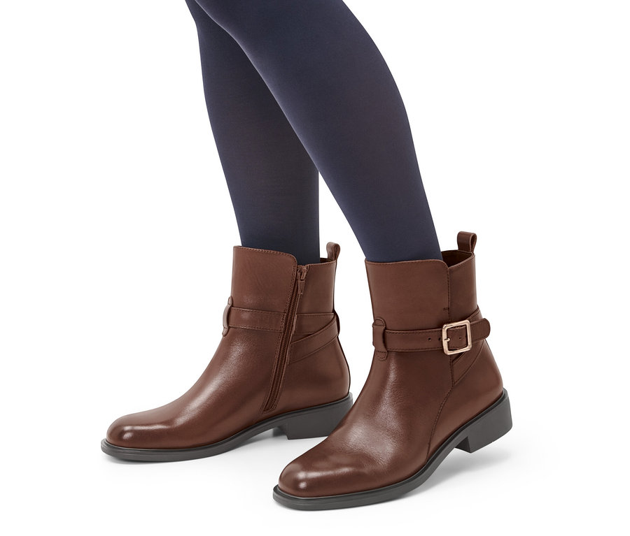 Beine mit dunkelblauen Strumpfhosen in braunen Leder-Boots.