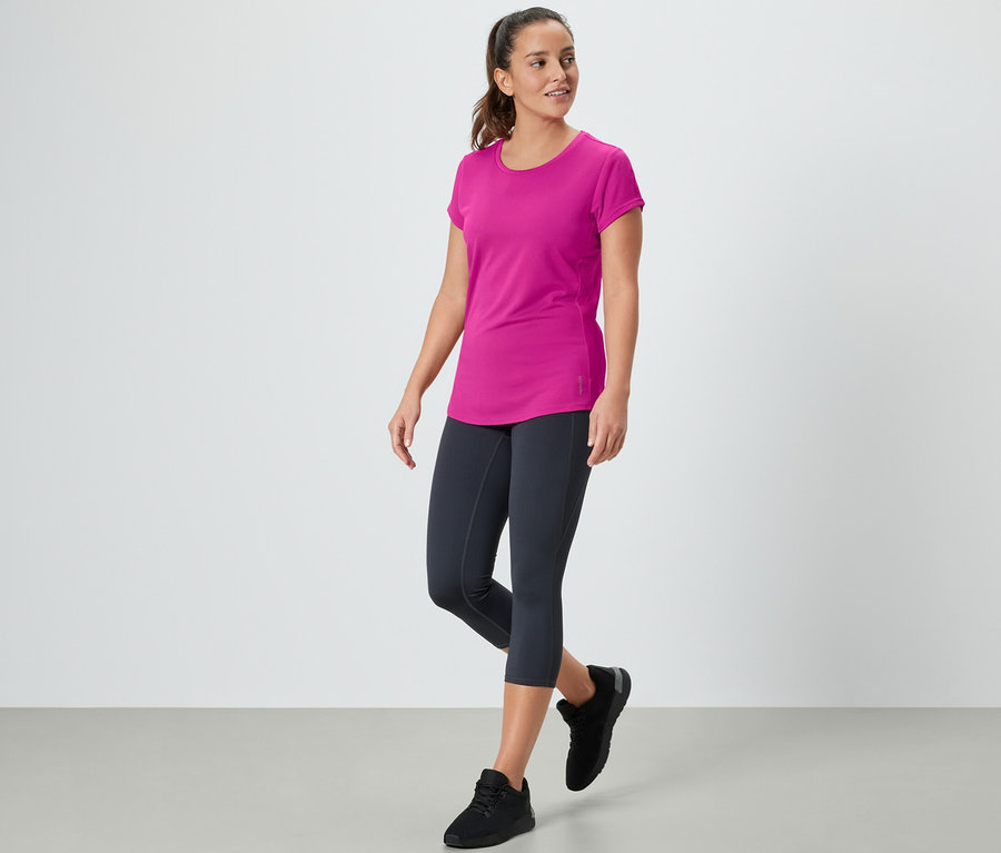 Eine Frau geht und trägt ein pinkes Sportshirt.