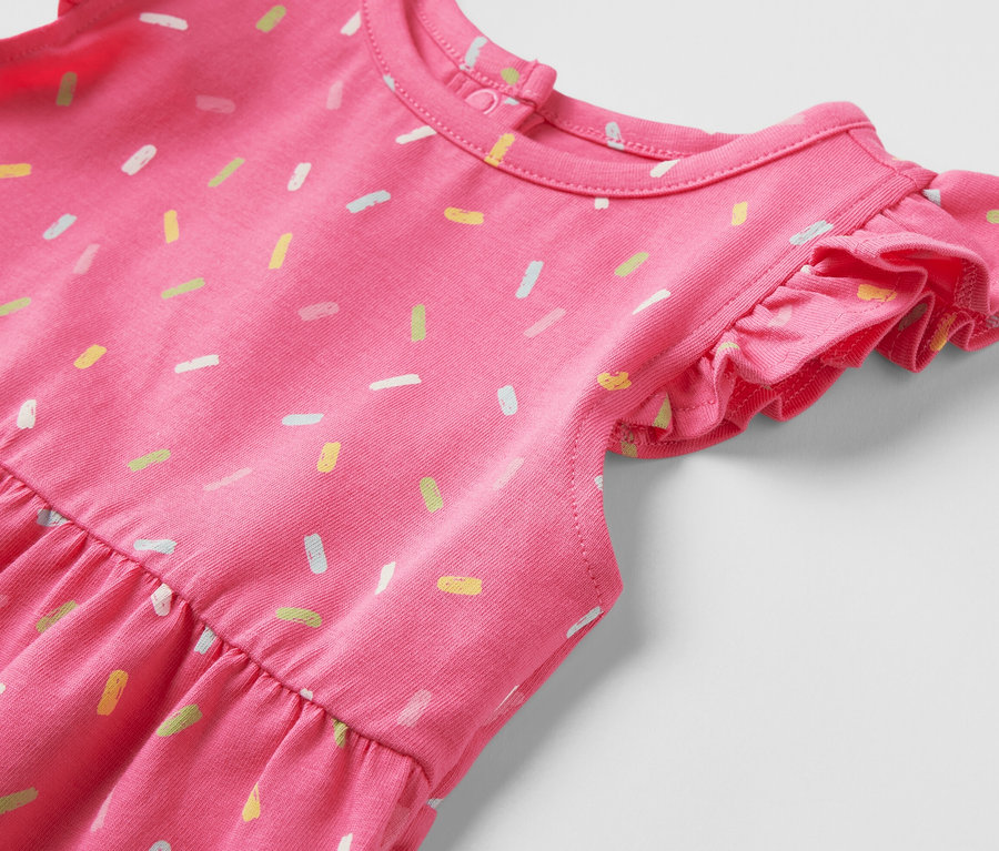 Detailansicht eines Kinder-Jerseykleids in Rosa mit bunten Streuseln.
