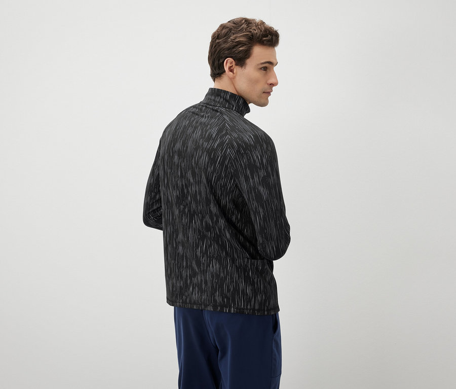 Mann schaut nach links und trägt ein schwarz-weißes Oberteil und blaue Hosen.