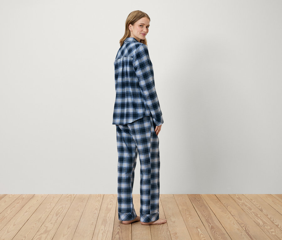 Frau posiert in blau kariertem Pyjama.
