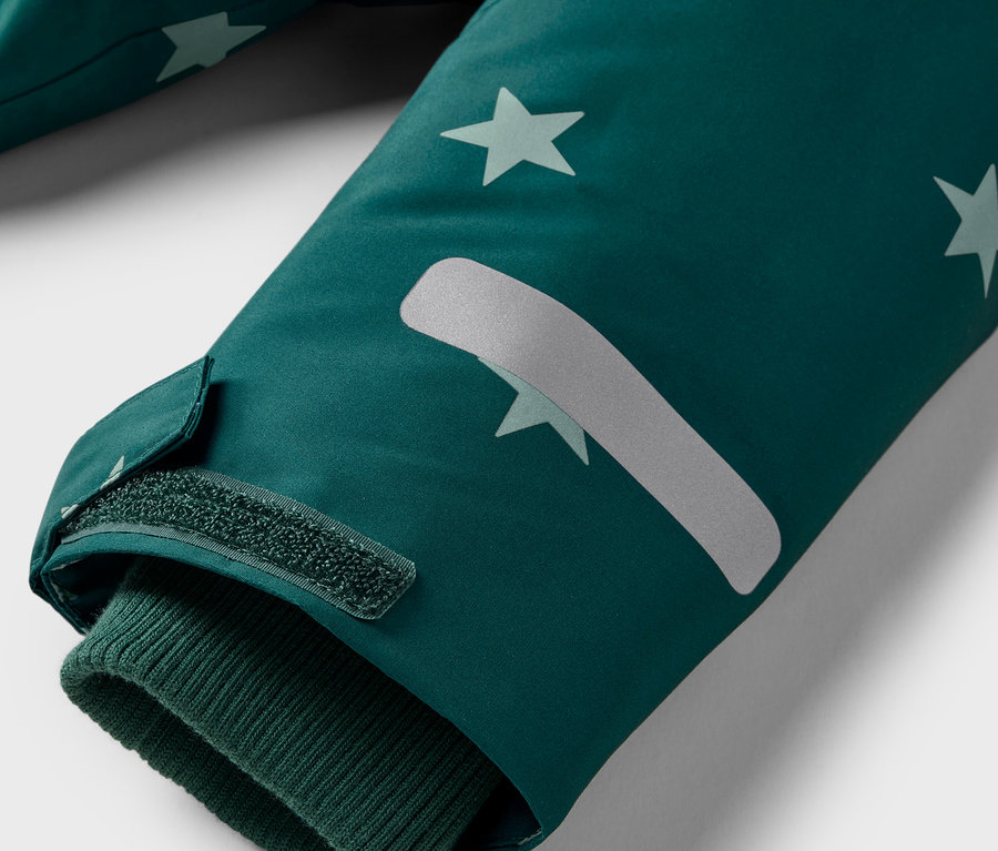 Detail eines Jackenärmels mit Sternen und Klettverschluss.