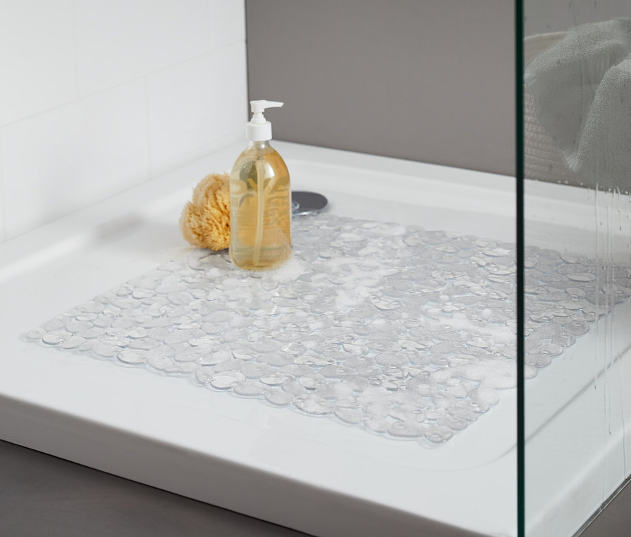 Duschwanne mit transparenter Duschwanneneinlage. Auf der Wanne liegen ein gelber Badeschwamm und eine Flasche mit Pumpspender.
