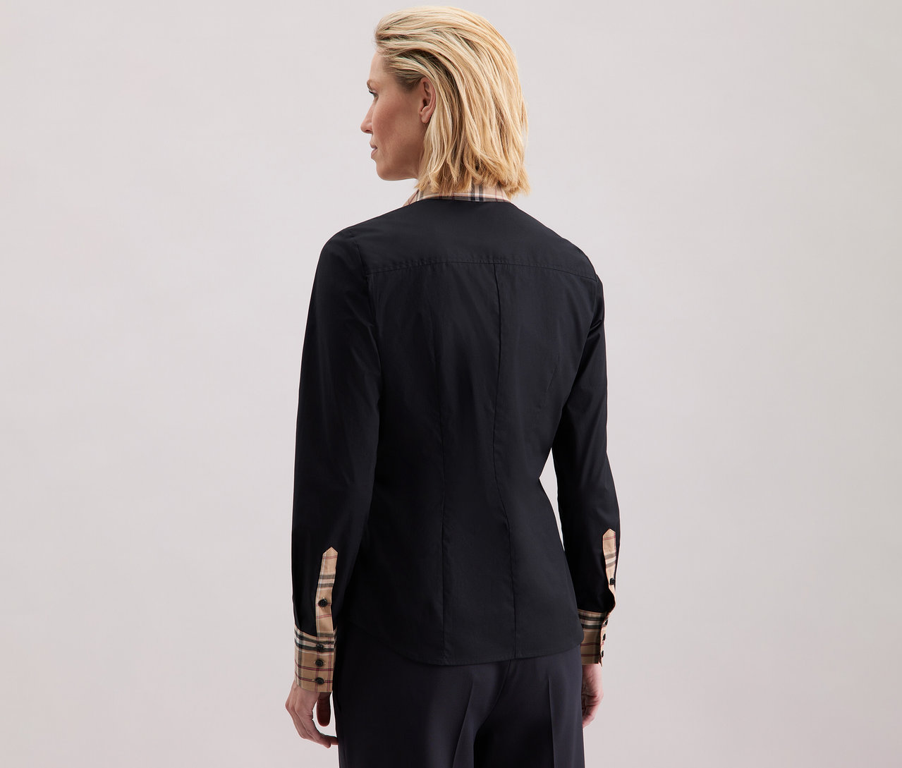 Eine Frau trägt eine Seidensticker Popeline-Bluse mit Karodetail.