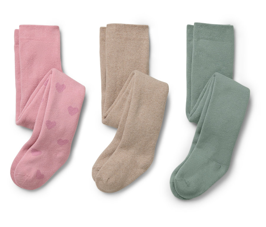 Zwei Kinderstrumpfhosen in Rosa mit Herzmuster und zwei in Beige und Grün liegen nebeneinander.