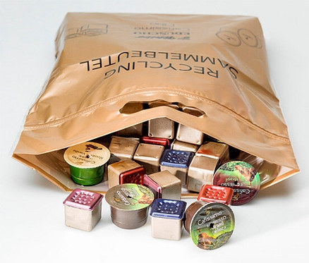 Offener, brauner Recycling-Sammelbeutel gefüllt mit gebrauchten Kaffeekapseln in verschiedenen Farben und Formen.