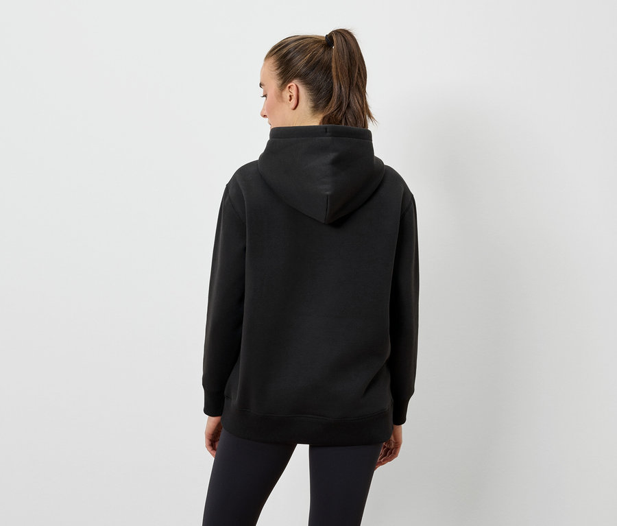 Frau von hinten trägt einen schwarzen Hoodie und schwarze Leggings.