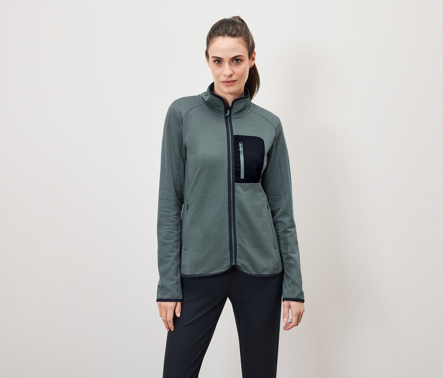 Frau trägt eine grüne Fleecejacke mit einer schwarzen Hose.