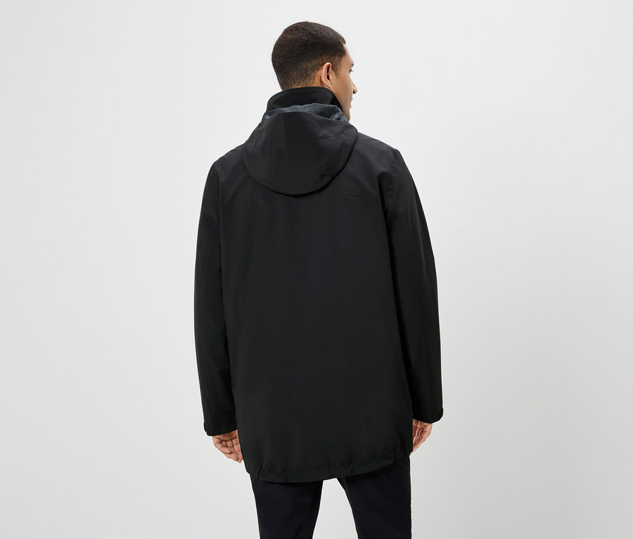 Mann von hinten trägt eine schwarze Jacke mit Kapuze und eine schwarze Hose.