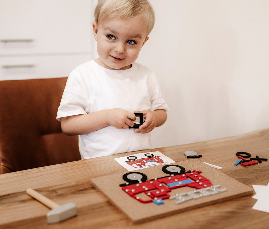 Ein Junge spielt mit dem small foot Hämmerchenspiel, Fahrzeuge der Stadt.