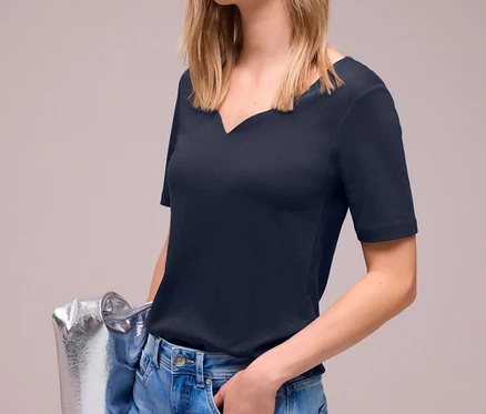Frau mit Street One Kurzarmshirt in Navy, Jeans und silberner Tasche.