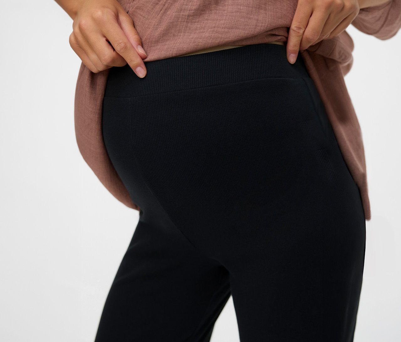 Frau zeigt die Taille der schwarzen, lockeren Leggins »MLEMILY« von MAMALICIOUS.