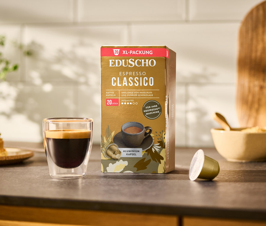 Ein Glas Espresso steht neben einer Packung EDUSCHO Espresso Classico mit 20 Kapseln.