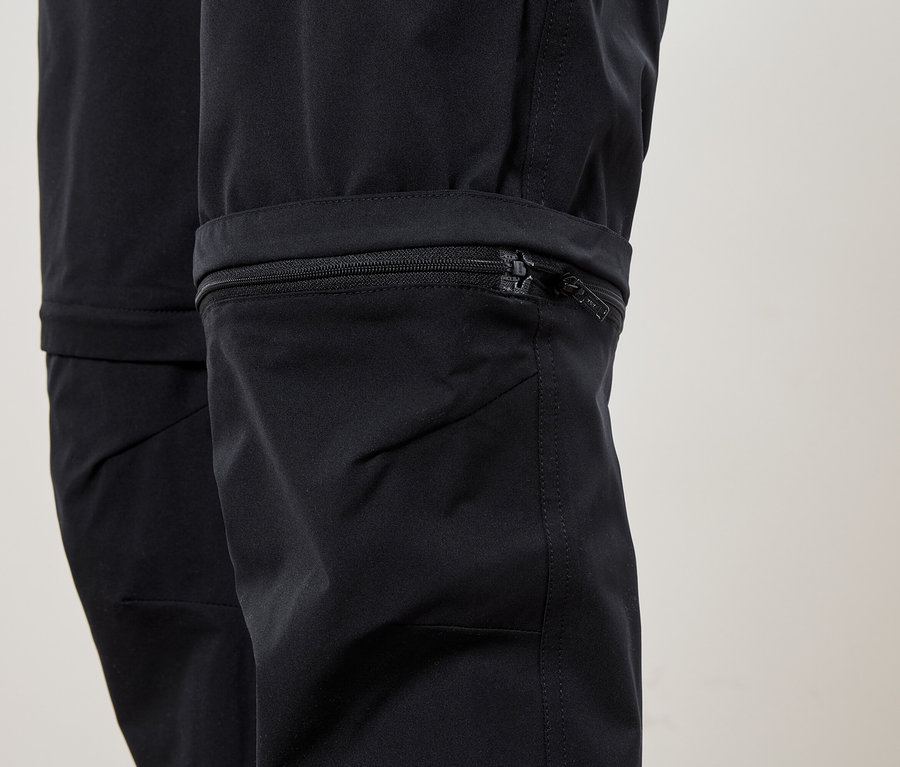 Nahaufnahme der Unterseite einer schwarzen Hose mit einem Reißverschluss am Bein.