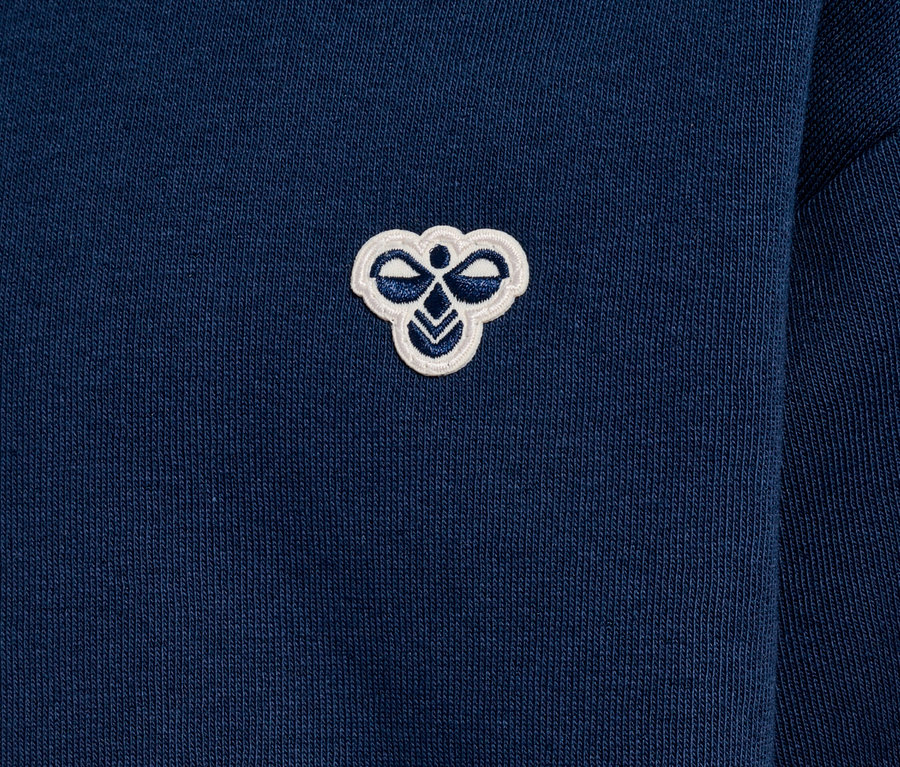 Nahaufnahme eines dunkelblauen Sweatshirts mit einem kleinen, gestickten, weißen Logo auf der Brust.