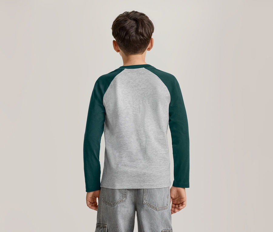Ein kleiner Junge von hinten, der ein langärmeliges Raglan-T-Shirt in Grau und Dunkelgrün sowie graue Shorts trägt.
