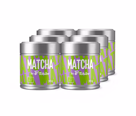Sechs silberne Dosen Tchibo Matcha Tee mit grün-violetten Etiketten, auf denen „MATCHA by Tchibo“ und „30g“ sowie ein Bio-Logo zu sehen sind.