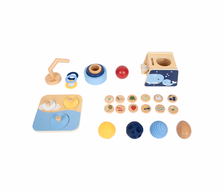 Eine small foot Baby-Box, 10–12 Monate, mit verschiedenen Holz- und Silikonspielzeugen: einer Wal-Steckbox, einem Stapelturm, einem Steckspiel mit Ringen, einem Puzzlebrett, illustrierten Scheiben und strukturierten Bällen.
