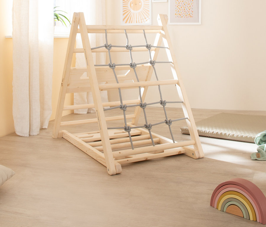 Ein roba Kletterdreieck aus Holz mit grauem Kletternetz im Kinderzimmer.