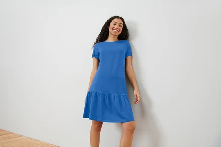 Frau posiert in kobaltblauem Jerseykleid mit Volant.