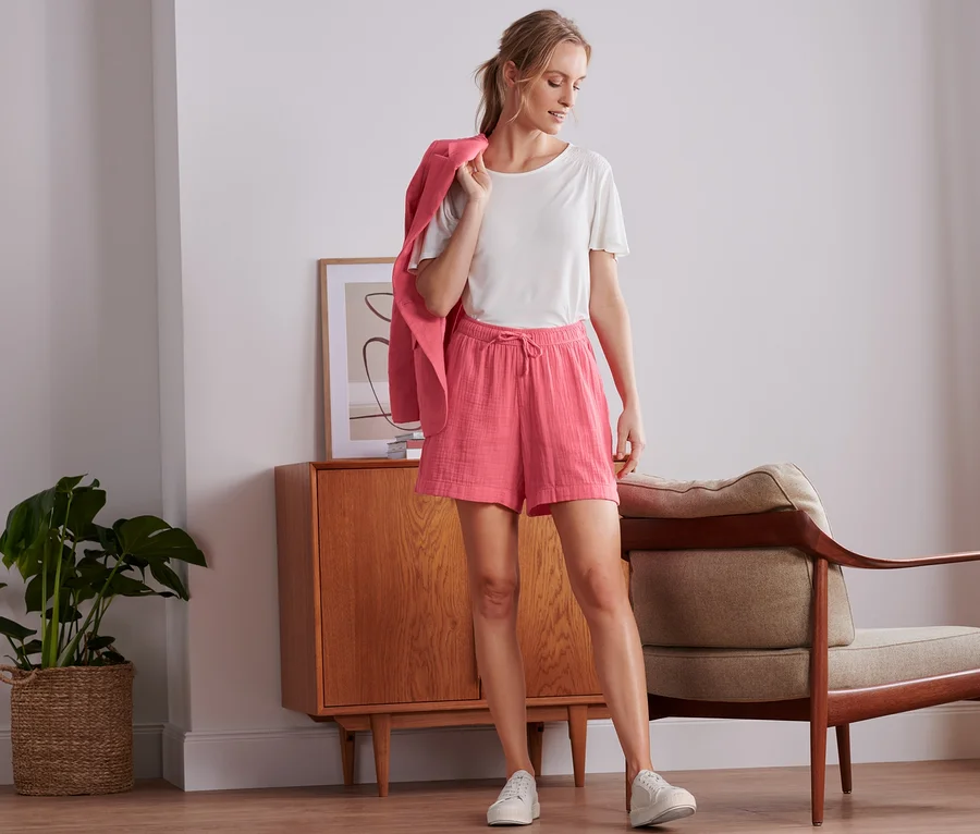 Frau steht und trägt Musselin-Shorts und einen Blazer.