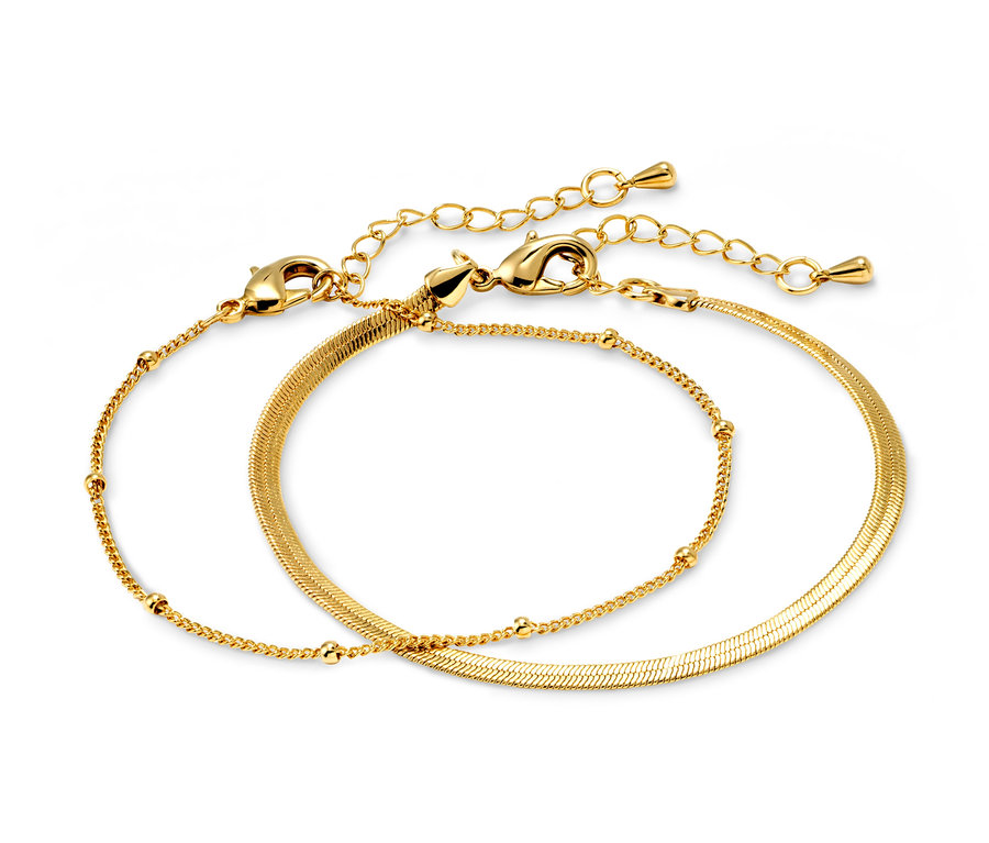 Zwei goldene Layer-Armbänder – Herringbone- und Kugelkette liegen auf einem weißen Hintergrund.