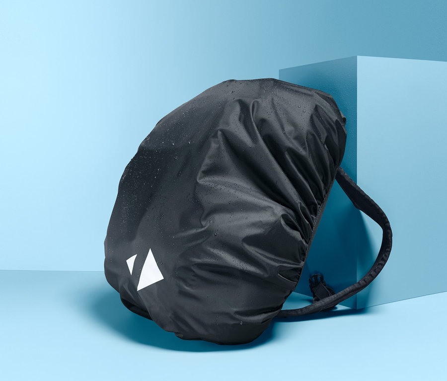Ein schwarzer Rucksack mit Rucksack-Regenschutzhülle vor blauem Hintergrund.
