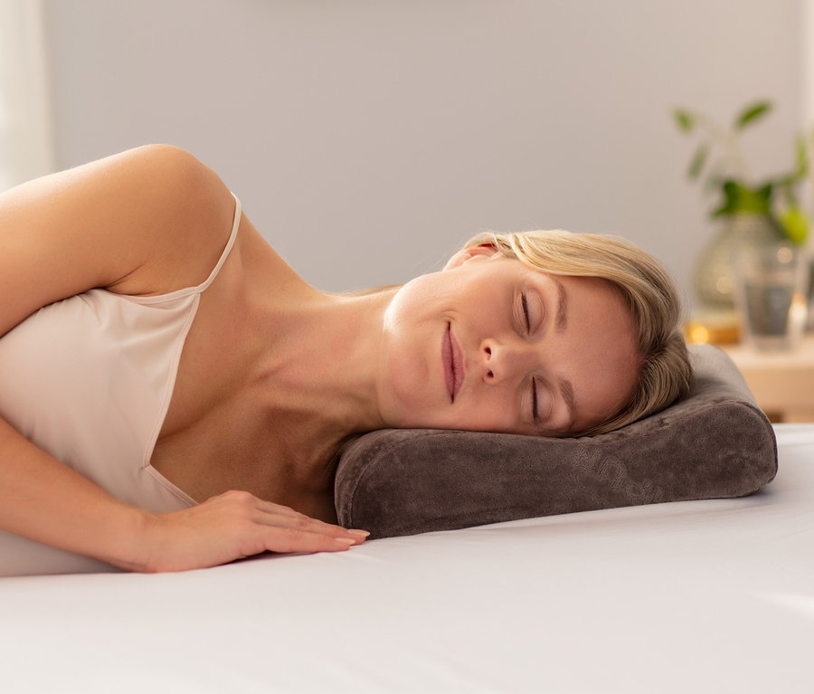 Frau schläft auf TEMPUR® Reisekissen auf einem Bett.