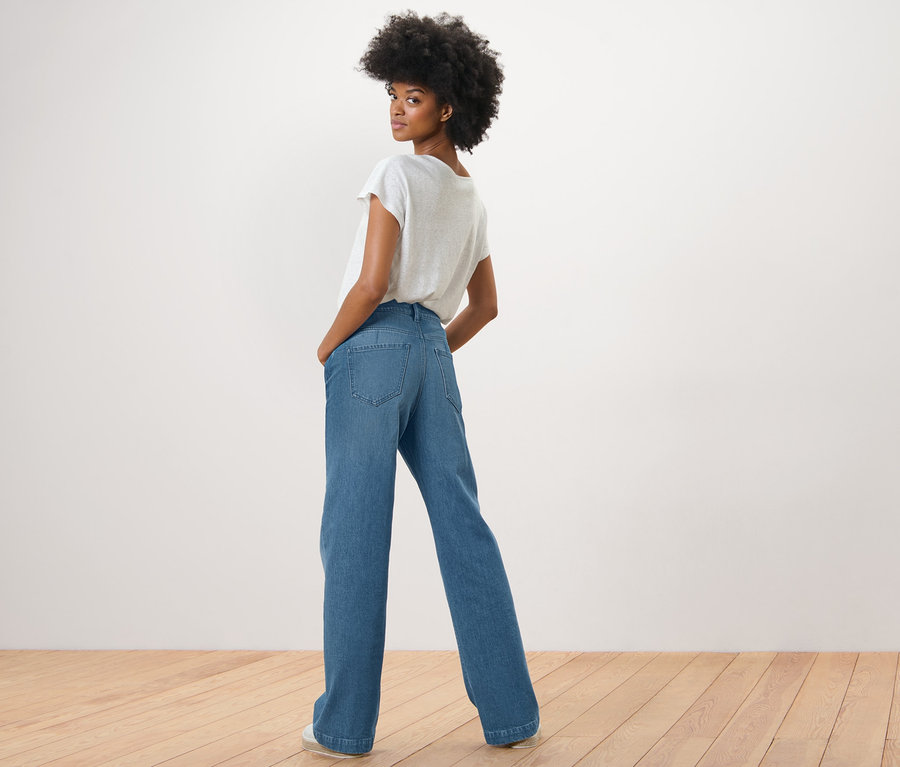 Eine Frau blickt über die Schulter und posiert in einer Palazzo Jeans ‒ Fit »Neni« und einem weißen T-Shirt.