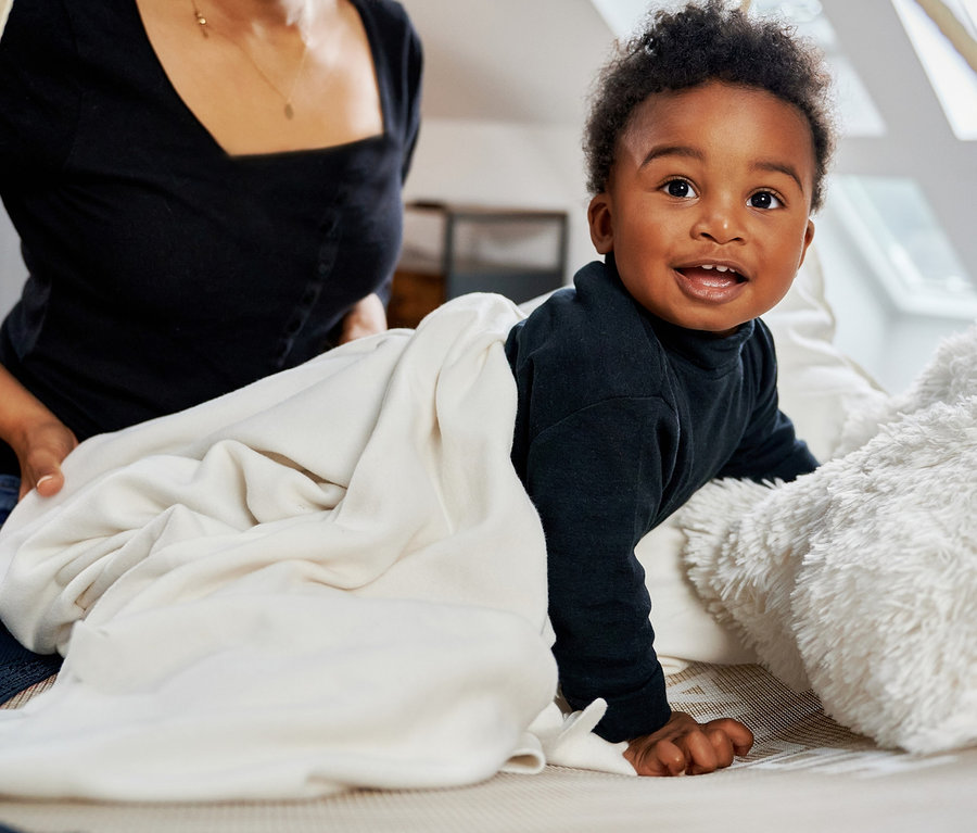 Eine Mutter lächelt ein krabbelndes Kind in einem schwarzen Outfit auf einer HUDORA Nestschaukel »Lounge« an.