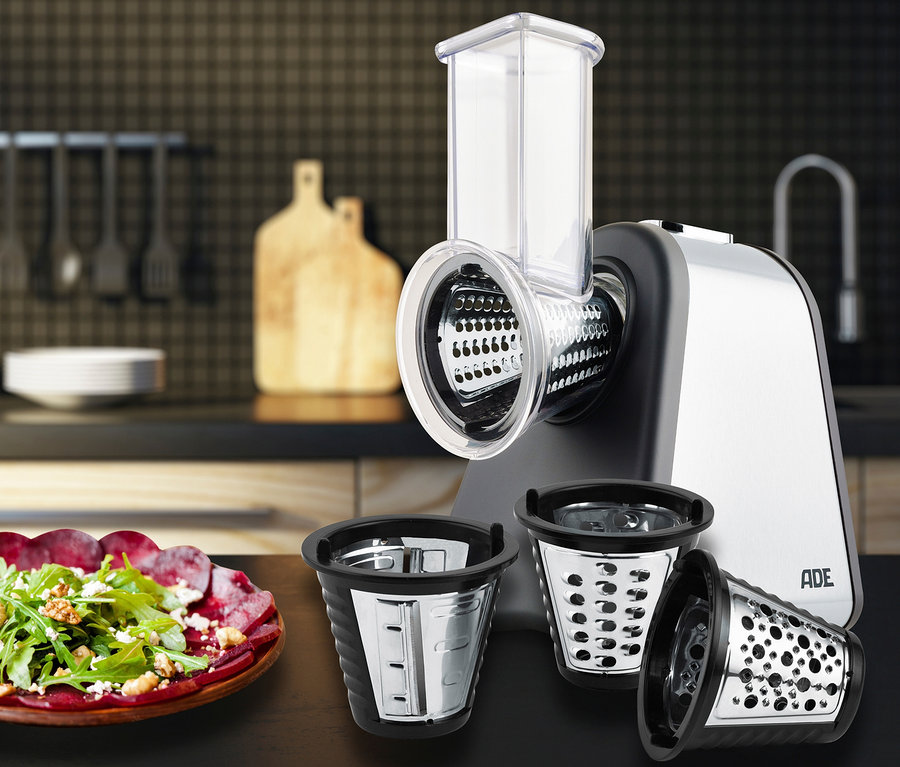 ADE Elektrische Reibe »KA1802« mit drei Aufsätzen auf einem Tisch neben einem Salatteller.
