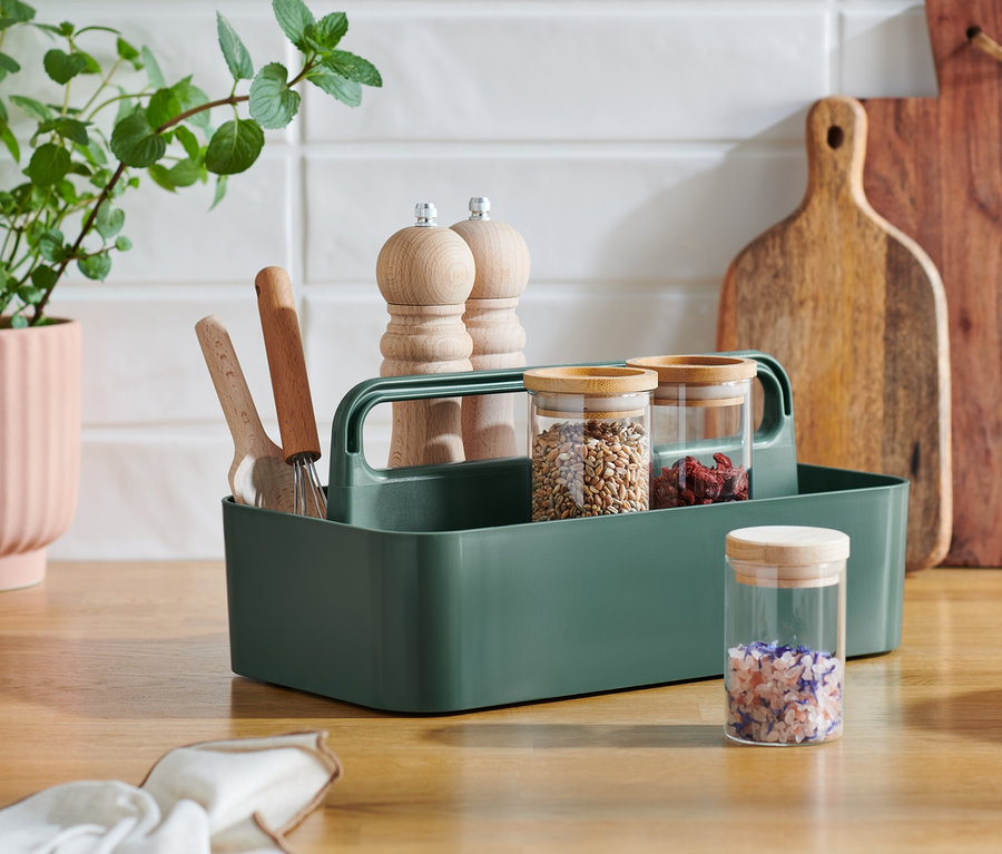 Mehrzweck-Korb steht auf der Küchentheke, daneben ein Blumentopf und Schneidebretter.