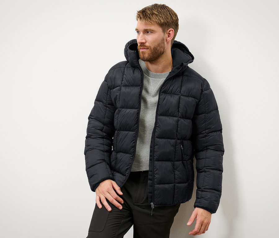 Mann trägt eine schwarze Steppjacke.