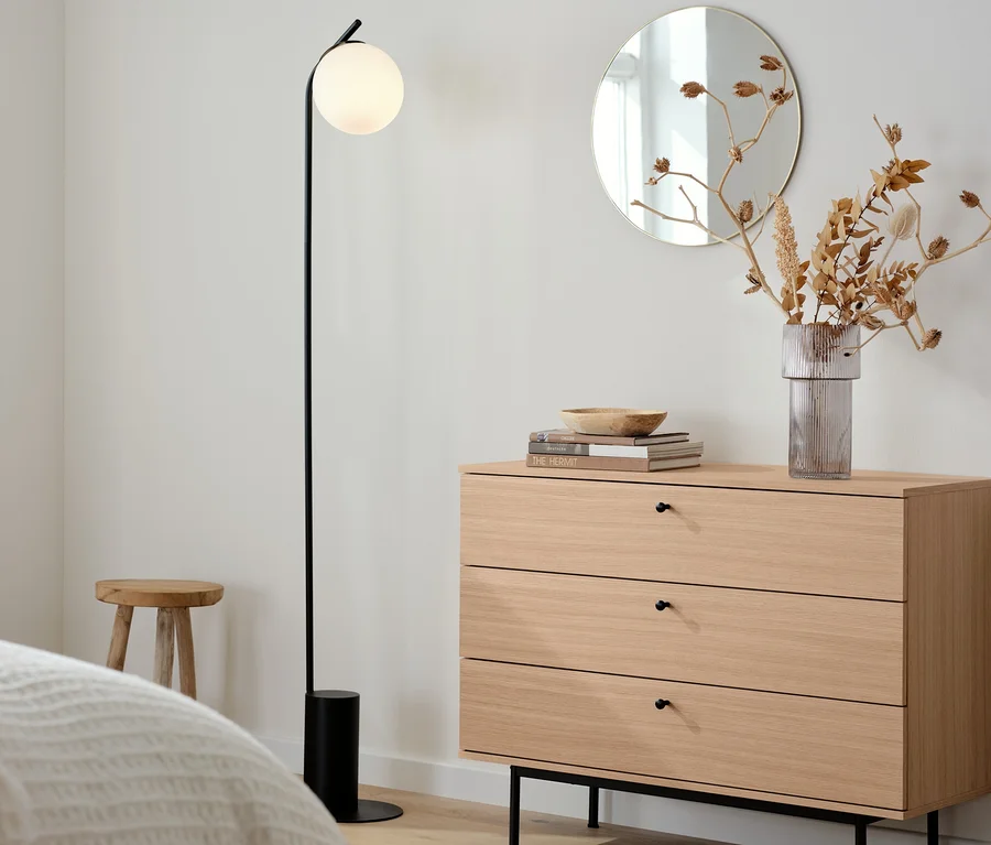 Kommode »Finnsbo« und eine schwarze Stehleuchte mit Glaskugel in einem Zimmer.