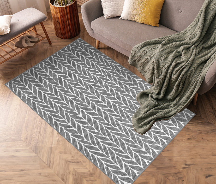 Wohnzimmer mit grauem Sofa, Topfpflanze und grau-weißem Outdoor-Wende-Teppich »Knitted Joy«.