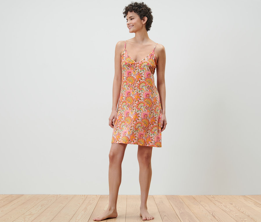 Frau steht und trägt ein Trägernachthemd mit Blumenmuster.