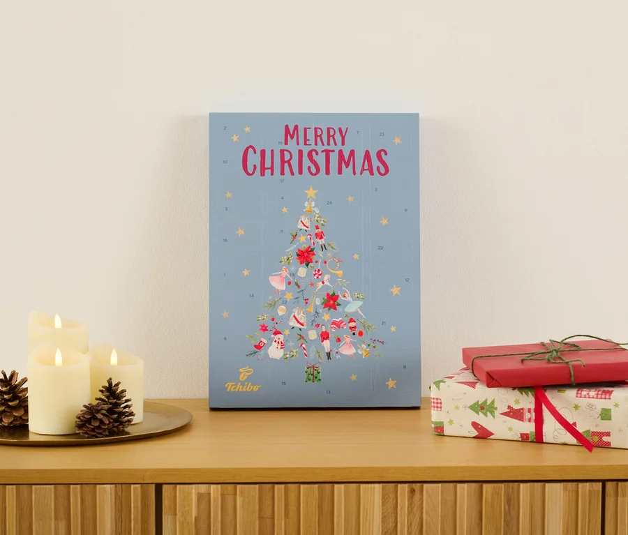 Tchibo Adventkalender steht auf einer Kommode neben Kerzen und Geschenken.