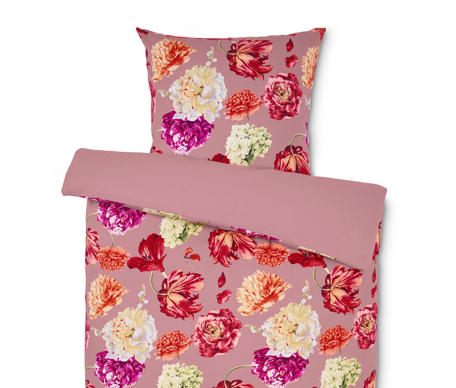Bettwäsche und Kissen mit Blumenmuster auf rosa Hintergrund.