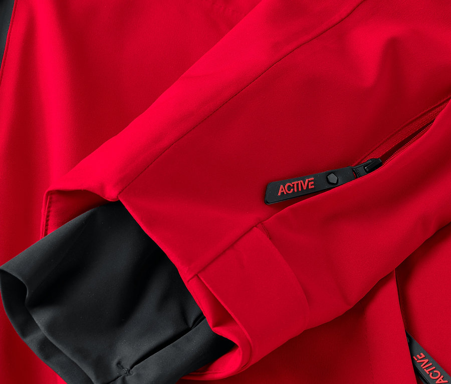 Detail einer roten Jacke mit schwarzen Elementen und einem Reißverschluss mit der Aufschrift ACTIVE.