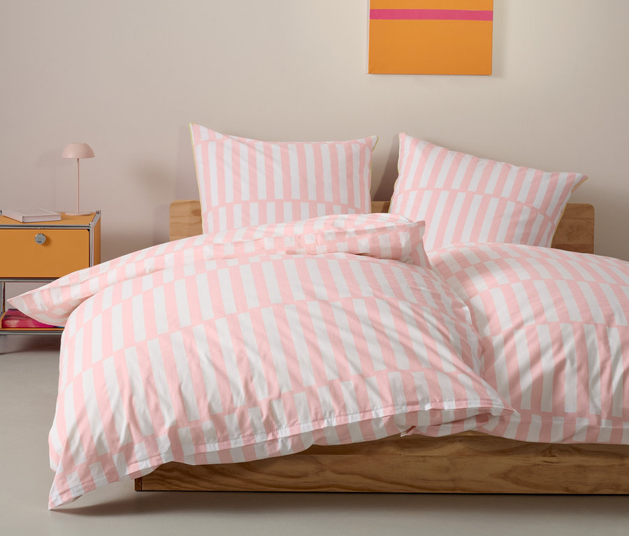 Rosa Renforcé-Bettwäsche in Normalgröße liegt auf einem Bett mit zwei Kissen.