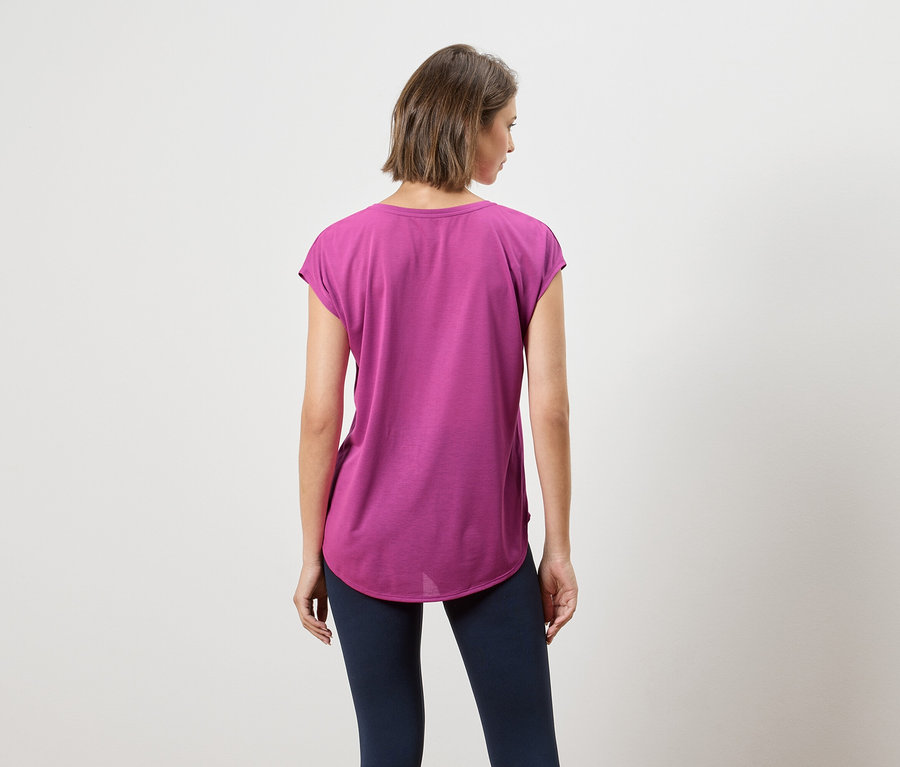 Rückansicht einer Frau mit kurzen braunen Haaren, die ein violettes T-Shirt und dunkelblaue Leggings trägt.