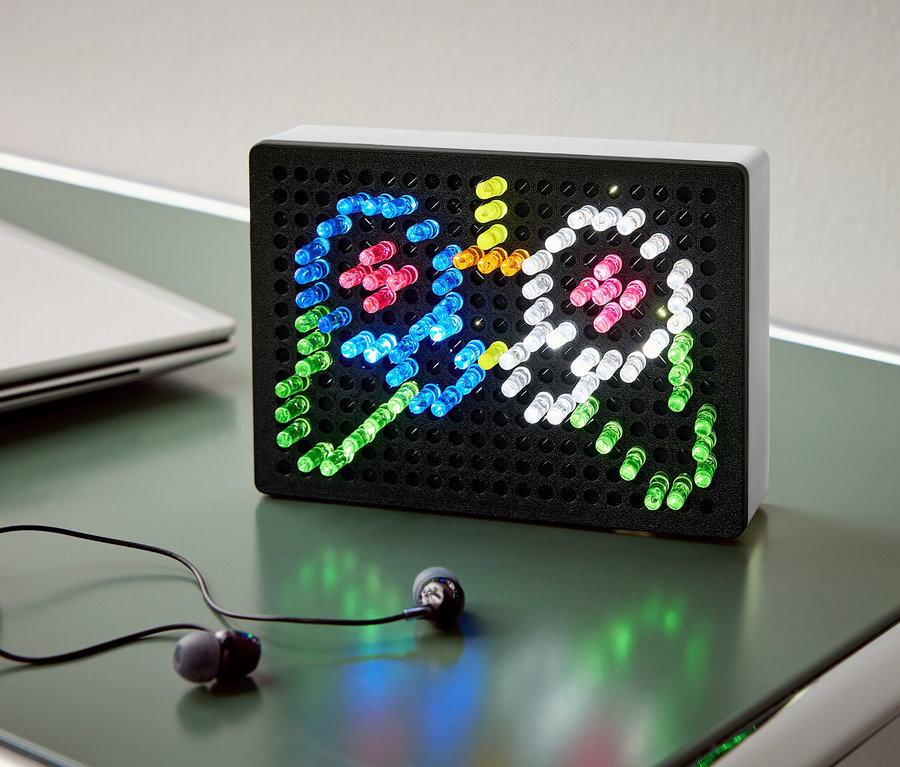 Auf einem Tisch stehen eine schwarze Leuchtbox mit bunten Lichtern, die zwei Geister darstellen, daneben Kopfhörer und ein Notebook.