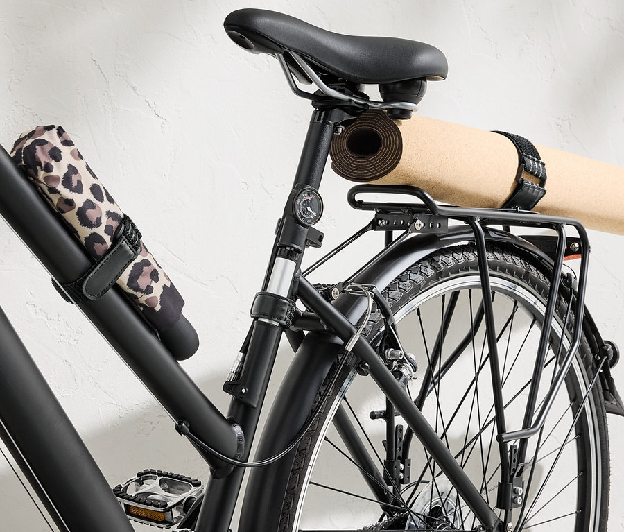 Schwarzes Fahrrad mit Yogamatte und Regenschirm, befestigt mit 6 elastischen Befestigungsgurten.