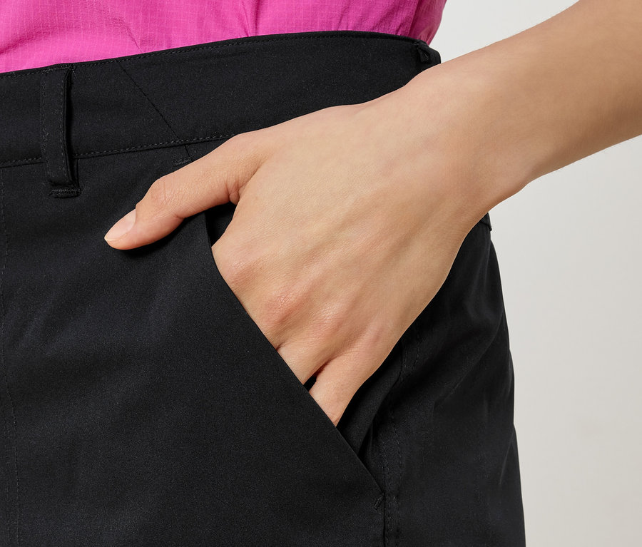 Frau mit Hand in der Tasche einer schwarzen Hose, dazu ein pinkes Hemd.