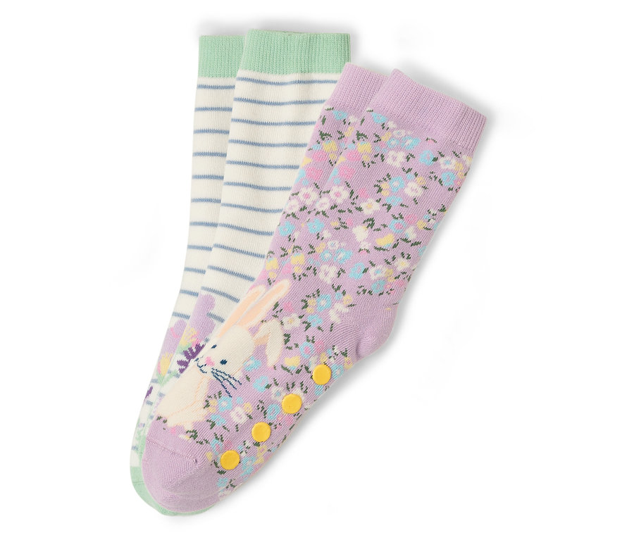 Drei Sockenpaare liegen auf einem weißen Hintergrund. Ein Paar ist lila mit einem Blumenmuster und einem Hasenaufdruck. Ein Paar ist weiß mit blauen Streifen und einem grünen Bund.