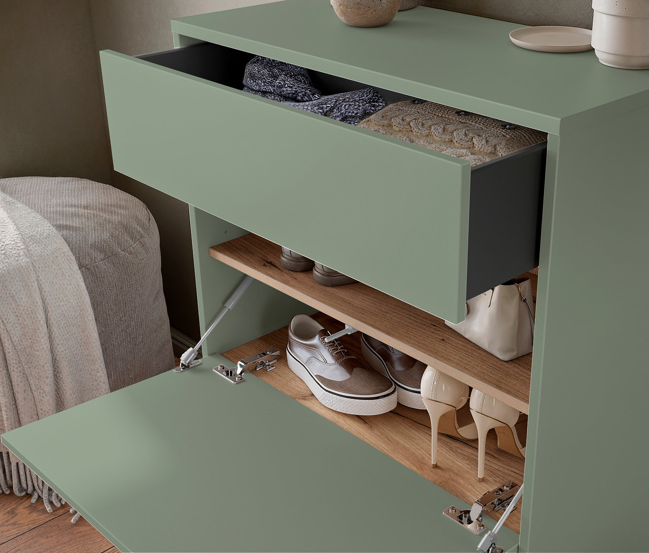 Grüner Schuhschrank mit geöffneter Schublade und Tür, gefüllt mit Kleidung und Schuhen.