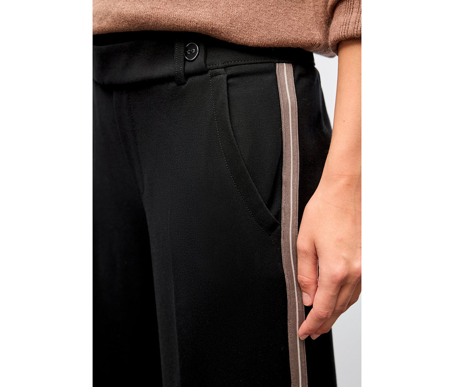 Nahaufnahme einer Person, die eine schwarze Street One Straight Leg Hose mit Gallonstreifen trägt.